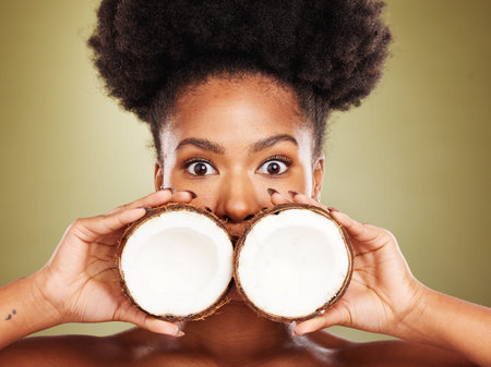 Skincare, beauty and portrait of black woman with coconut in studio on brown background. Wellness, body care and eyes of girl with fruit for healthy, organic and natural cosmetic products and makeupの写真素材