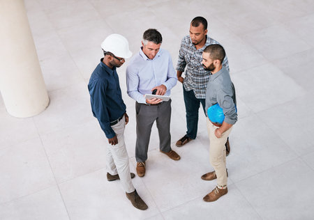 Theres an app for everything these days. a group of male architects looking at a tablet together...