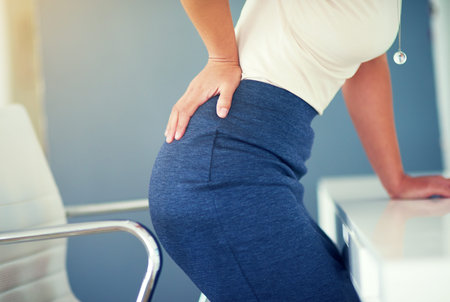 Shes been in that chair too long. a young businesswoman holding her lower back in discomfort.