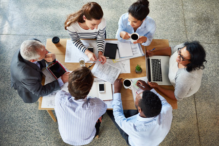 Planning starts in the boardroom. High angle shot of a group of coworkers sitting around a table in the boardroom.の写真素材