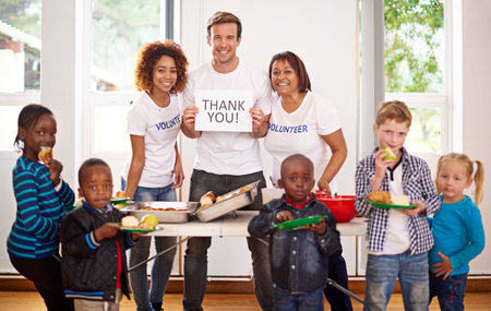 Thank you for your generosity. Portrait of a volunteer holding up a thank you sign while feeding...