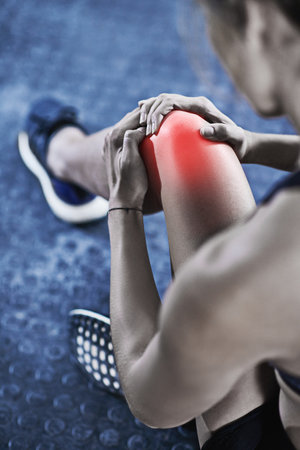 It hurts now, but one day itll be your warm up. a young woman holding her injured knee thats highlighted in red.の写真素材