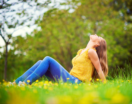 What a life. a carefree young woman relaxing in a field of grass and flowers.の写真素材
