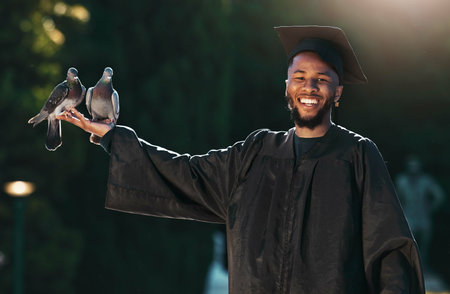 Student portrait, graduate and pigeon with a smile, hat and cloak for graduation, celebration and achievement outdoor in park. University, college or school man with happiness for education successの写真素材