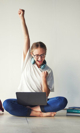 Laptop, success and woman getting news of scholarship, loan approval or email with good news against wall with mockup. Student, winner and excited girl with winning fist for exam, results and reviewの写真素材