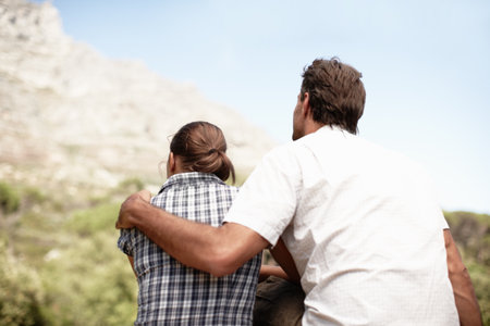 Sharing a breathtaking view. Rear view of a couple out enjoying a mountain view after a hike.の写真素材