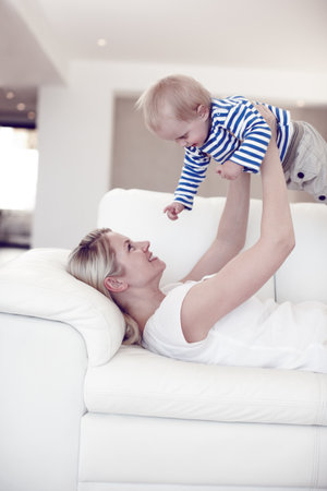 Wheee. Cropped view of an attractive young mother lifting her cute baby boy as she lies on the sofa.の写真素材