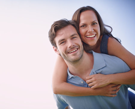 Keeping the romance alive. A handsome man piggybacking his loving wife outdoors.の写真素材