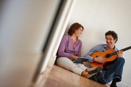 Shes in love with a guitar player. a woman using her digital tablet while her husband plays the guitar.の写真素材