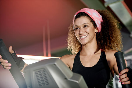 Every workout is worth it. a young woman working out with a stepping machine at the gym.の写真素材