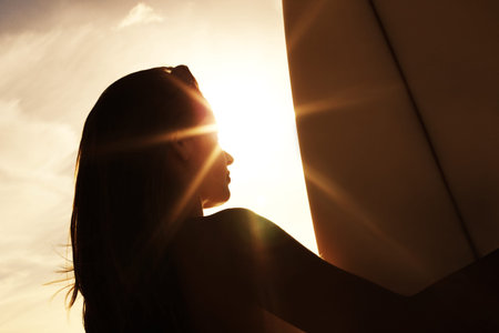 Young woman standing with a surfboard - Outdoor. Rear view of a young woman standing with a...