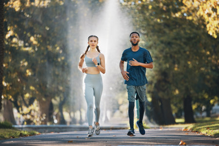 Couple running, fitness and runner in park for exercise and cardio with body training outdoor. Interracial, black man and woman run in nature, workout and sports for healthy active lifestyle.の写真素材