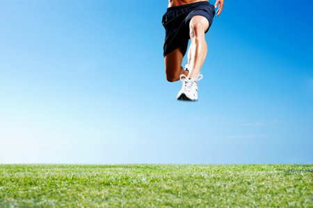 Young guy jumping on the grass against the sky. Cropped image of a young guy jumping on the green...