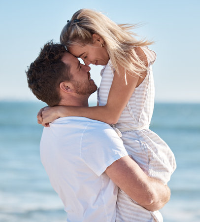 Beach, couple and hug, lifting and love, care and romantic date, summer vacation and sunshine holiday. Happy couple, man and woman at ocean, freedom and travel, honeymoon resort and tropical sea funの写真素材