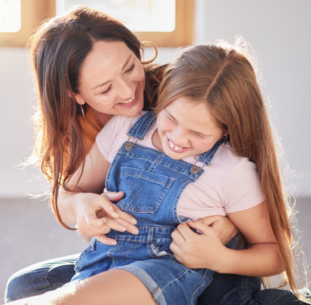 Happy, love and mother bonding with her child while playing, laughing and relaxing together at their home. Happiness, smile and woman being playful with her girl kid in their modern house in Canada.の写真素材