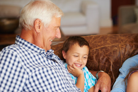 He means the world to me. a little boy sitting beside his grandfather on the sofa.
