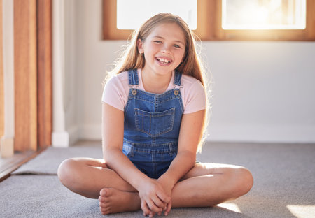 Portrait of happy girl, kid and child on living room floor, carpet and ground for fun, play and happiness alone. Excited youth, smile children and one female relax in lounge, house and family homeの写真素材