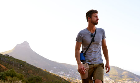 He comes for the view. a handsome young man enjoying the view while hiking.