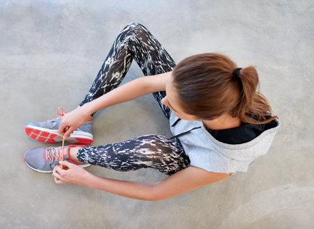 Time for her daily workout. High angle shot of a young woman tying her shoelaces before a workout.