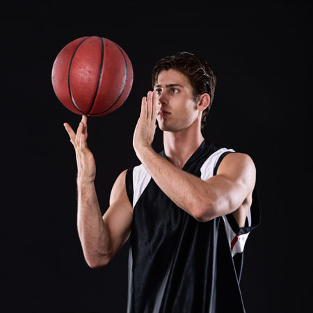 Now thats some skill. A young athlete spinning a basketball on his finger against a black...