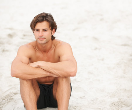 Sandy reflection. a handsome young man enjoying a relaxing day at the beach.の写真素材