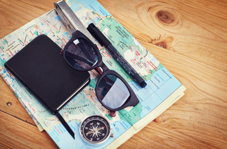 Ready for a day of exploring. High angle shot of sunglasses, a notebook, a compass and utility tool...