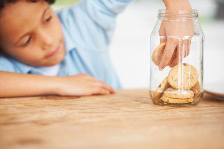 Mmm, so many cookies just for me. A cute young boy grabbing a cookie from the cookie jar.の写真素材