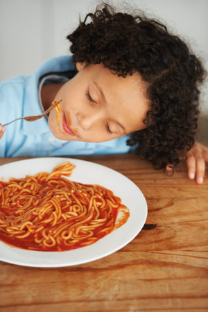 Spaghetti is my favourite. A cute young boy eating spaghetti with his eyes closed.の写真素材