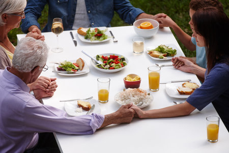 Thankful for what theye about to eat. a multi-generational family saying grace before sharing a meal.の写真素材