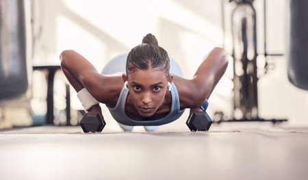 Dumbbell, fitness and black woman training, workout or bodybuilder in gym floor portrait for body...