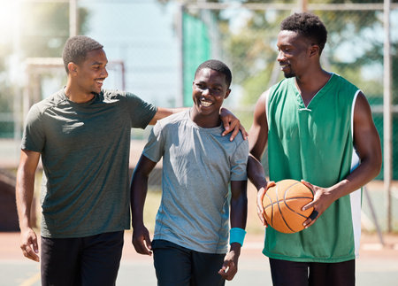 Basketball player, happy friends and walking together in conversation, training or exercise in summer. Team happiness, basketball court and basketball for black man group, outdoor or game in sunshineの写真素材