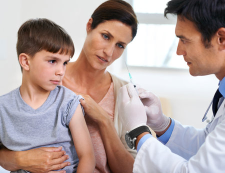 Time to bring out my inner superhero. a mother and son watching the doctor prepare the needle for an injection.の写真素材