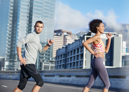 Keeping pace. two friends jogging together through the city streets.