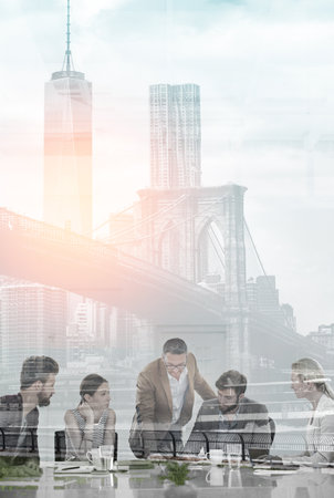 Big city ambition. Multiple exposure shot of colleagues having a meeting superimposed over a city background.の写真素材
