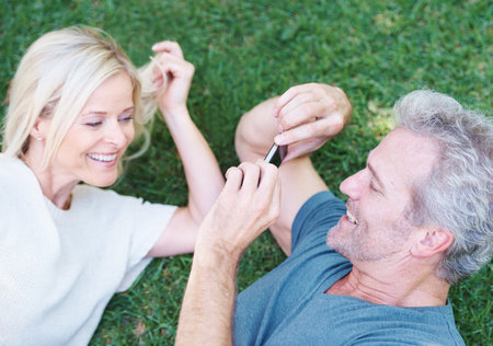 Youre always the focus of my gaze. A mature man taking a picture of his beautiful wife while lying on the grass.の写真素材