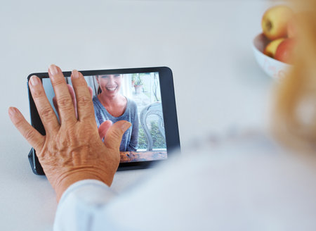 Distance makes the heart grow fonder. Rearview of a senior woman in a video converce with her grandchild.の写真素材