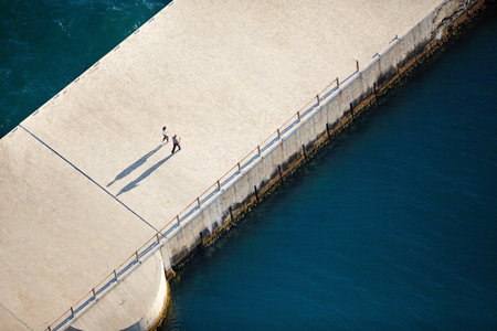 Walking along the pier. Aerial view of two people walking along a pier.の写真素材