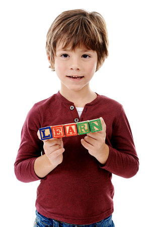 Playing is all about the building blocks to growth. Studio shot of a cute little boy holding building blocks that spell the world learn against a white background.の写真素材