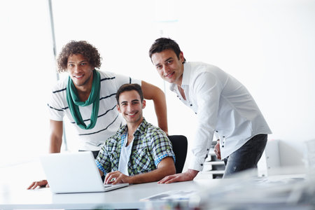 Theyve got a great team dynamic. Three male coworkers working in the office together.