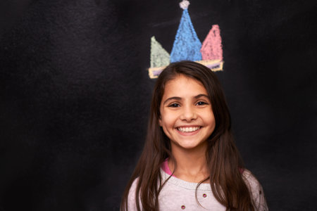 A princess keeps her head up so her crown wont fall off. Portrait of a young girl standing in front...