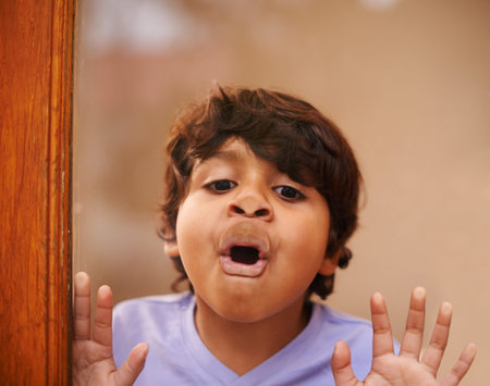 Look, Im a fish. A cute little boy pulling a face against a glass window.