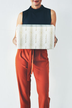 Woman holding, box or gift in studio for birthday, christmas or celebration with fashion, clothes or...