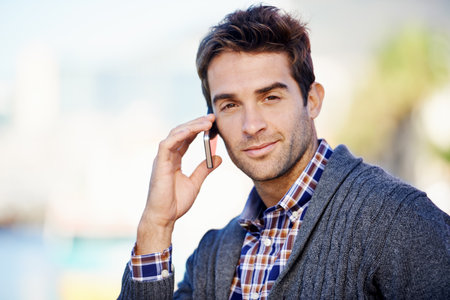 Keep yourself connected. a handsome young man making a call on his mobile phone outdoors.の写真素材