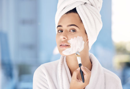 Woman, skincare brush and facial cream, portrait and cosmetic beauty routine. Moisturizer, health and model in morning face treatment to relax in home with towel, self care and cosmetic treatmentの写真素材