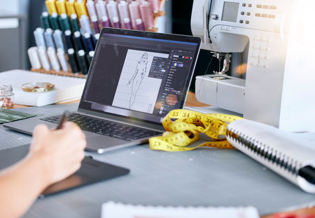 Fashion, designer and laptop for a sketch or drawing for clothes manufacturing in a tailor workshop or factory for creative ideas. Hand of woman at desk with design technology for illustration workの写真素材
