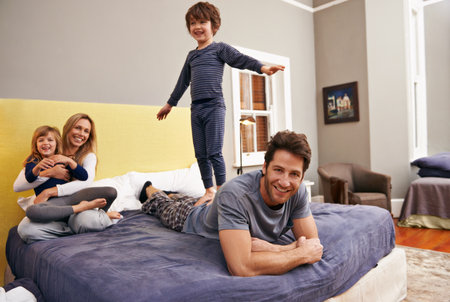 Family bonding time. Portrait of a young family bonding at home in their bedroom.の写真素材