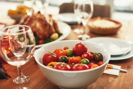 Food, traditional and celebration with tomato on table for thanksgiving, meal and luxury, turkey and nobody. Chicken, nutrition and family lunch setup for christmas, sunday or family reunion partyの写真素材