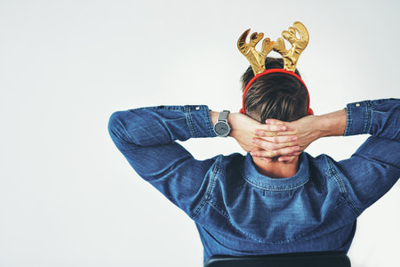 Businessman, relax and christmas reindeer antlers on office mockup background, company wall space or small business startup. Creative designer, hands behind head and done with festive season successの写真素材