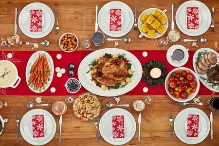 Christmas, party and food with a festive feast on a dinner table in a home from above for celebration. Chicken, event and nutrition with a meal setting on a wooden surface in the holiday seasonの写真素材