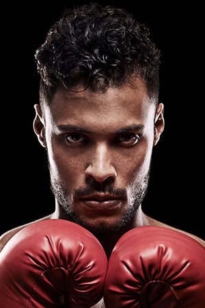 Know yourself and you will win all battles. Portrait of a young man wearing boxing gloves against a black background.の写真素材